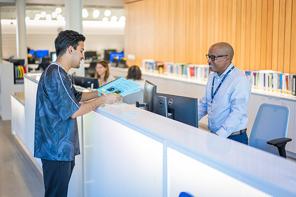 Librarian at a desk helping a student