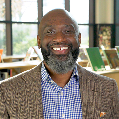 dual enrollment alum milton mitchell smiles in his elementary school's library
