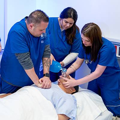 Respiratory care students work with a mannequin patient