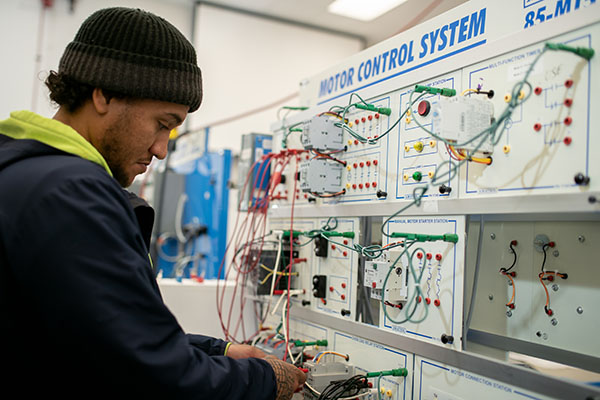 Trades student operating motor control system